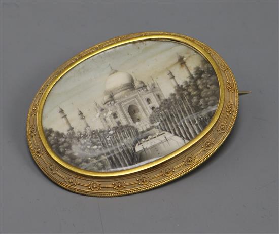 An Indian oval miniature on ivory painted with the Taj Mahal in a yellow metal mount, 72mm.